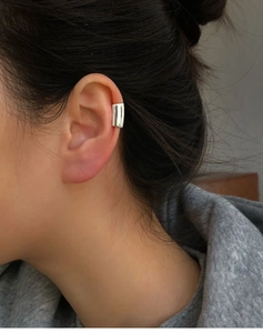 Close-up of minimalist silver metal ear cuff on model showing smooth rectangular design