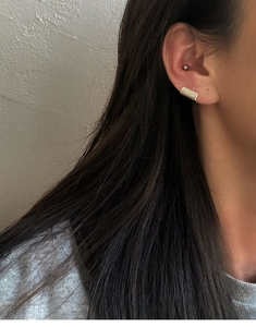 Close-up of geometric silver metal ear clips and stud set on a model ear