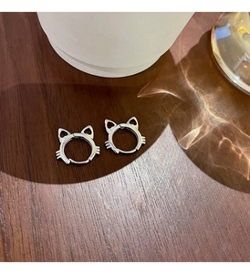 Detailed view of silver s925 cat-shaped hoop earrings on a warm wooden surface