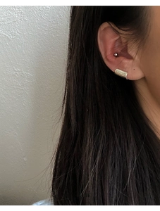 Minimalist gold ear cuff in sleek cylindrical design worn on female ear cartilage