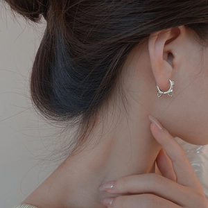 Detail shot of cute S925 silver cat-shaped hoop earrings worn by a model in warm light