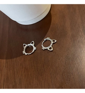 Close-up of cat-ear shaped s925 silver hoop earrings with whiskers detail on wood