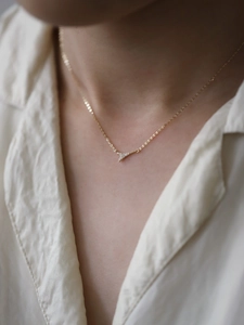 Close-up of golden Eiffel Tower pendant with white zircon inlays on cross chain