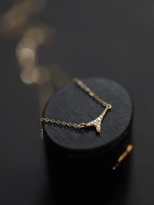 Macro shot of Eiffel Tower pendant necklace with pavé zircons on premium black leather box