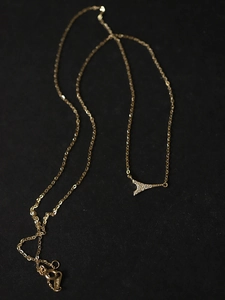 Detailed macro view of Eiffel Tower pendant with pavé set zircon stones on golden chain