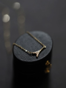 Macro shot of gold Eiffel Tower necklace with micro-pave crystals on black jewelry box