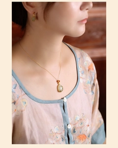 Close-up of vintage Hetian jade necklace with blue floral enamel on elegant gold setting