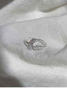 Detail of silver crescent moon ring with sparkling zircon stones and textured metal band
