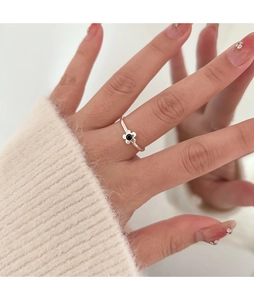 Close-up of adjustable silver flower ring with black petals and enamel center on hand