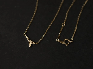 Macro shot of gold Eiffel Tower necklace pendant with sparkling zirconia on fine O-chain