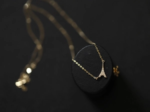 Detailed macro shot of a gold Eiffel Tower pendant necklace with sparkling pavé crystals