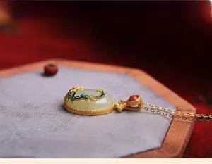 Macro shot of white jade pendant with enamel inlay and red agate bead on a purple base