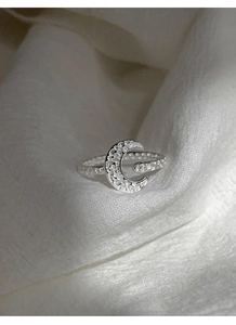 Macro shot of silver crescent moon ring with micro-set zircons and textured band surface