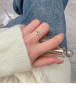 Detailed view of silver flower ring with black gemstone on a woman's finger