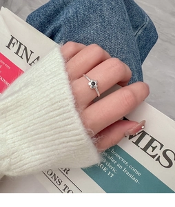Close-up of silver daisy flower ring with black core worn by a model in casual attire