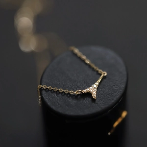 Elegant gold Eiffel Tower necklace with micro-pave crystals on premium black leather stand