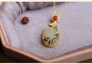 Macro detail of Chinese style gold necklace with white jade pendant and enamel floral pattern