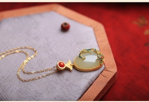 Detail of Chinese style white jade necklace with gold matte finish and red gemstone