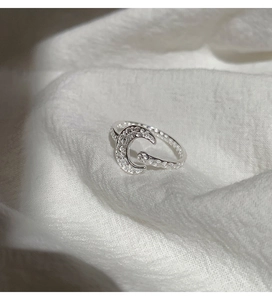 Detailed view of silver moon ring featuring white zircon stones on white fabric