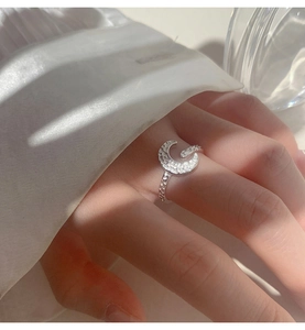 Close-up of crescent moon ring with hammered texture and white cubic zirconia accents