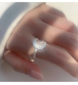 Macro detail of textured crescent moon ring with silver finish and sparkling crystals