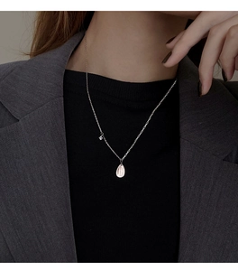 Detail of silver teardrop necklace with small zircon on fine chain worn by a model