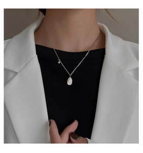 Detail of silver teardrop pendant necklace with zircon and engraving on model