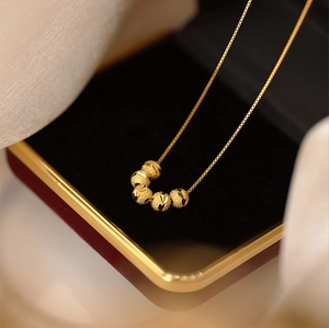 Vue détaillée du pendentif doré à cinq perles avec texture givrée sur velours rouge