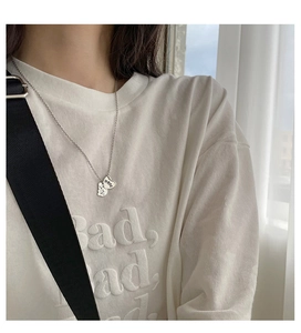 Détail d'un collier argenté avec un pendentif en cœur et un petit charme de nuage