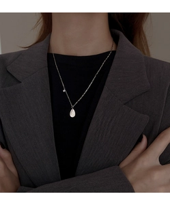 Detailed close-up of a silver teardrop pendant with zircon on a fashion chain necklace