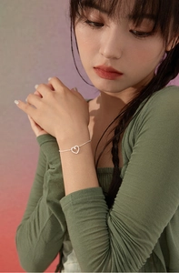 Dettaglio del bracciale con pendente a cuore in argento e zirconi indossato da una modella