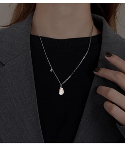 Detail view of silver teardrop necklace with zircon stitching on a gray blazer suit