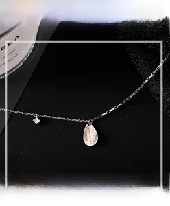 Detail of silver teardrop pendant with engraved phrase and zircon on a minimalist chain