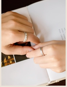 Gros plan d'un couple portant des bagues vintage en argent mat avec calligraphie chinoise