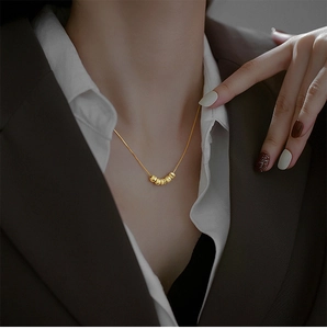 Gros plan d'un collier ras du cou doré avec cinq perles polies sur le cou d'une femme