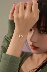Dettaglio di un bracciale a cuore in argento con zirconi scintillanti al polso di una modella