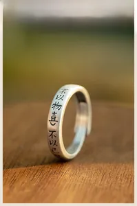 Détail d'une bague chinoise rétro mate avec calligraphie Zen gravée sur socle en bois