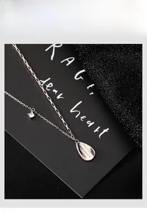 Detailed macro of vintage silver water drop pendant with engraved romantic quote