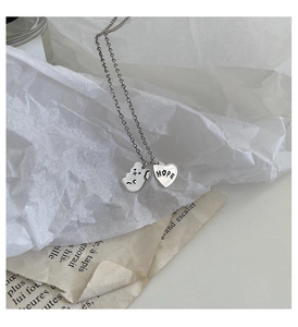 Vue détaillée du pendentif chien et du cœur gravé HOPE en métal argenté sur chaîne