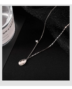 Detail shot of silver water-drop necklace with polished tag and zircon on dark texture