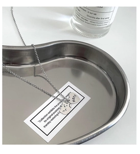 Gros plan du collier argenté avec cœur Hope et pendentif chat sur plateau en métal