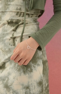 Primo piano di un bracciale con ciondolo a cuore minimalista e catena a sfere d'argento