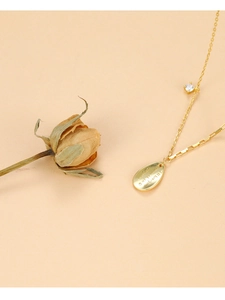 Detailed close-up of gold teardrop necklace with zircon inlay and engraved romantic quotes