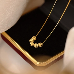 Collier doré élégant avec cinq perles texturées sur présentoir en velours noir