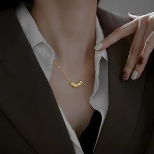 Collier minimaliste en or avec six perles sur une chaîne fine porté par un mannequin