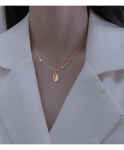 Detail of vintage gold teardrop necklace with zircon on an asymmetrical chain link