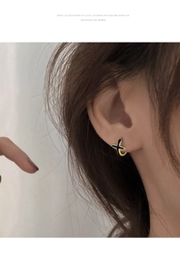 Gros plan de boucles d'oreilles croix noires minimalistes avec anneau plaqué or