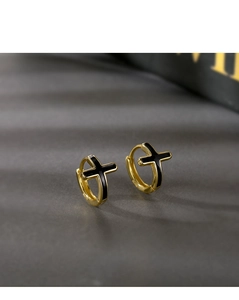 Détail de boucles d'oreilles croix dorées avec émail noir et poinçon en argent S925 visible