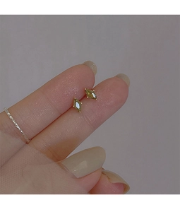 Macro detail of olive green marquise-cut zircon stud earrings held by hand