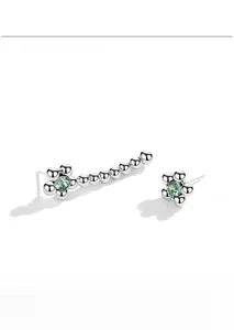 Gros plan sur les boucles d'oreilles fleurs en argent S925 avec cristaux verts